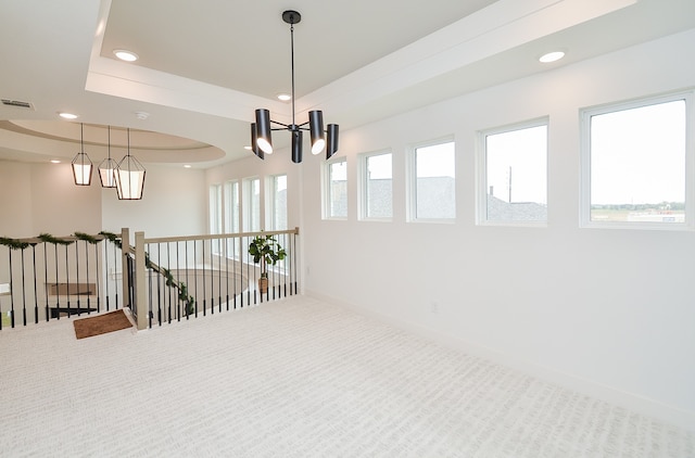 hall with carpet flooring, a healthy amount of sunlight, and a notable chandelier