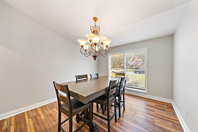 dining space featuring a textured ceiling, hardwood / wood-style floors, a chandelier, and lofted ceiling