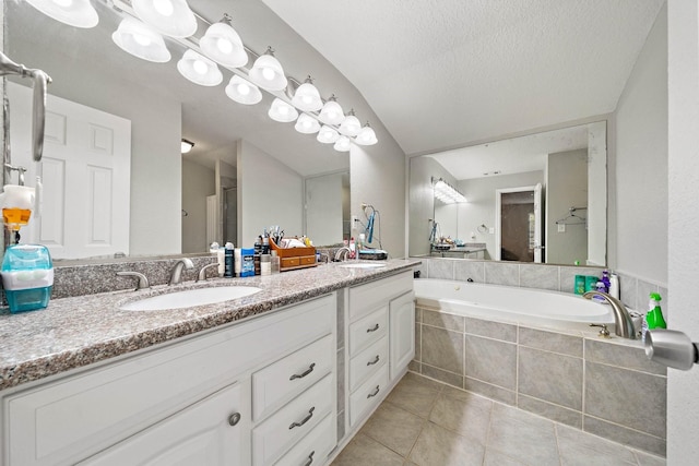 bathroom featuring tiled tub, tile patterned flooring, vanity, and a textured ceiling