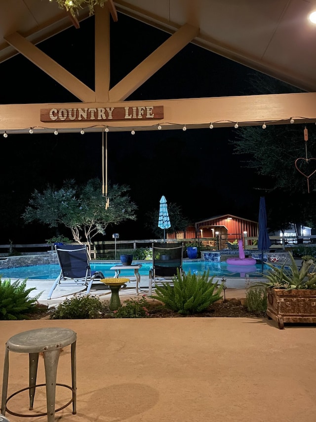 pool at night with a patio area