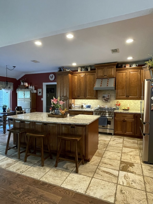 kitchen with a kitchen island, lofted ceiling, a breakfast bar area, and appliances with stainless steel finishes