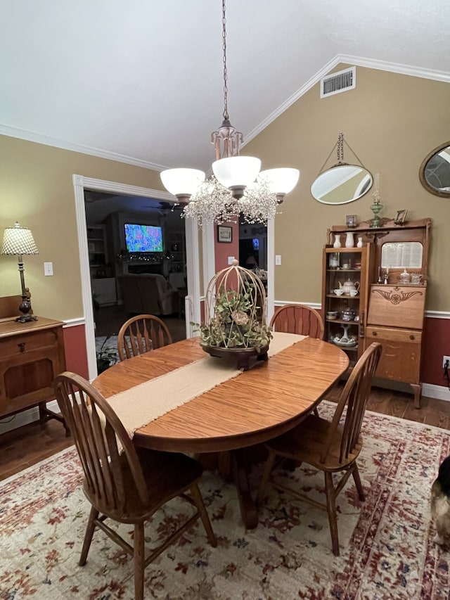 dining area with wood-type flooring, lofted ceiling, and ornamental molding