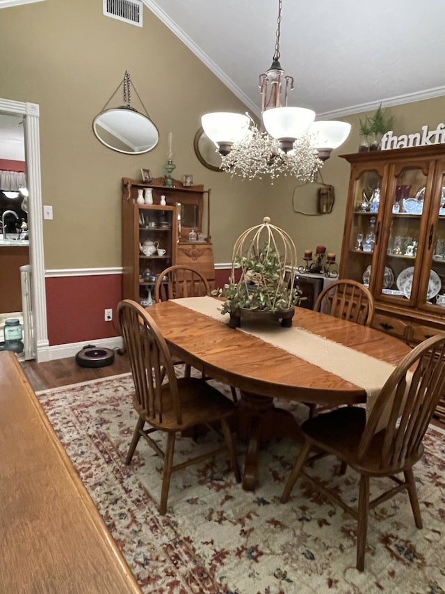 dining area featuring wood-type flooring, ornamental molding, and a chandelier