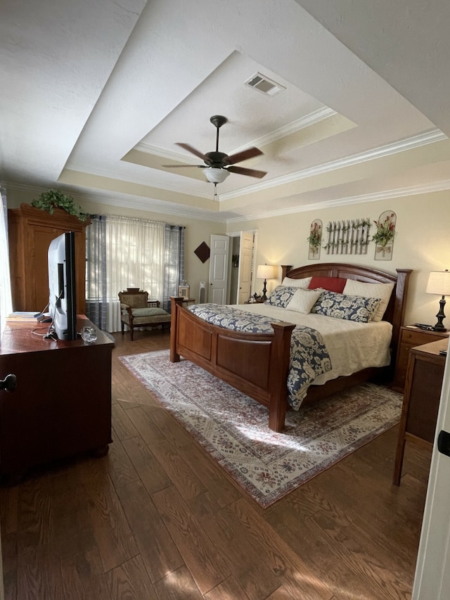 bedroom with hardwood / wood-style flooring, ceiling fan, ornamental molding, and a tray ceiling