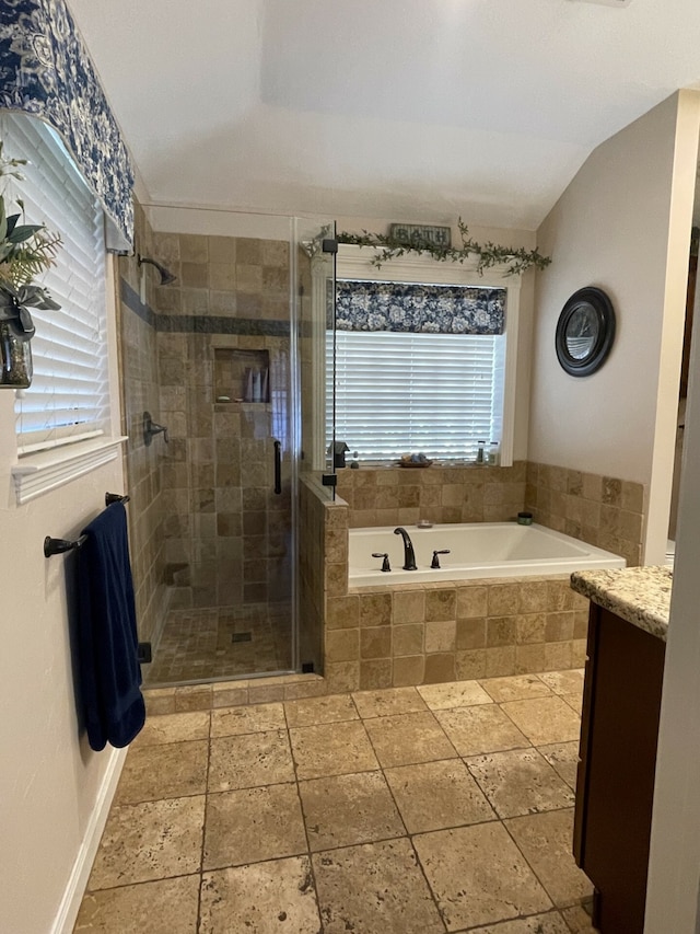 bathroom with independent shower and bath, vanity, vaulted ceiling, and a healthy amount of sunlight