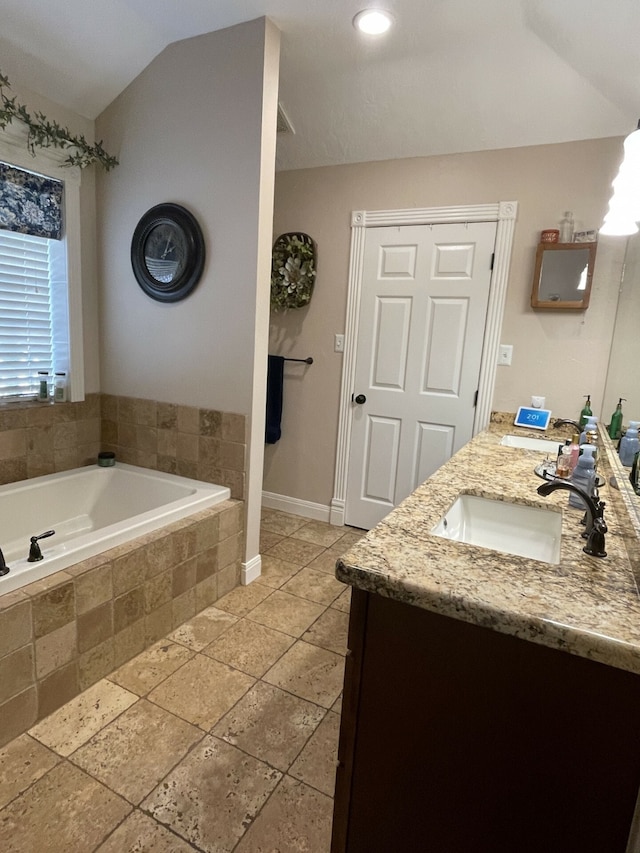 bathroom featuring vanity, a relaxing tiled tub, and lofted ceiling