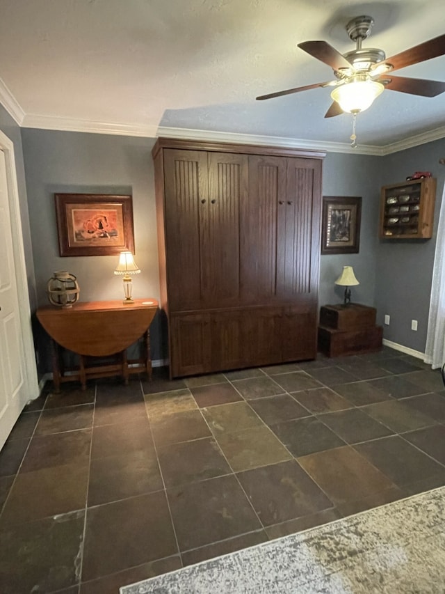 interior space with dark tile patterned flooring, ceiling fan, and ornamental molding