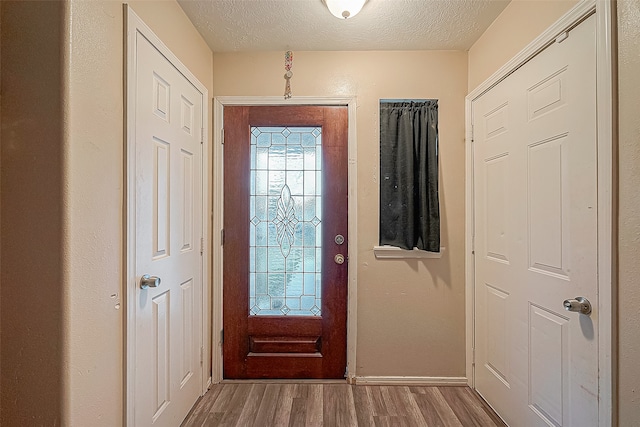 foyer with light wood-type flooring and a textured ceiling