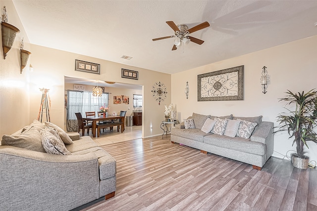 living room featuring wood-type flooring, a textured ceiling, and ceiling fan