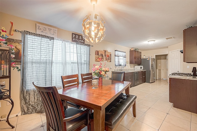 dining area featuring sink, light tile patterned floors, and a chandelier