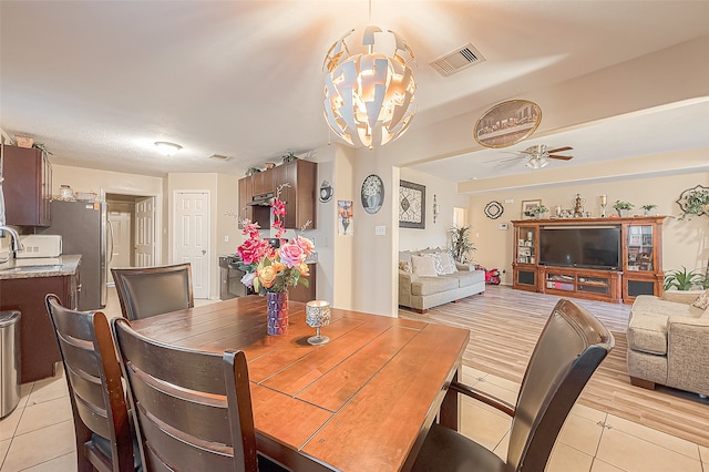 dining room with ceiling fan with notable chandelier and light wood-type flooring