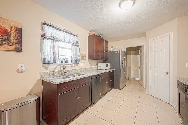 kitchen with appliances with stainless steel finishes, a textured ceiling, dark brown cabinetry, sink, and light tile patterned floors