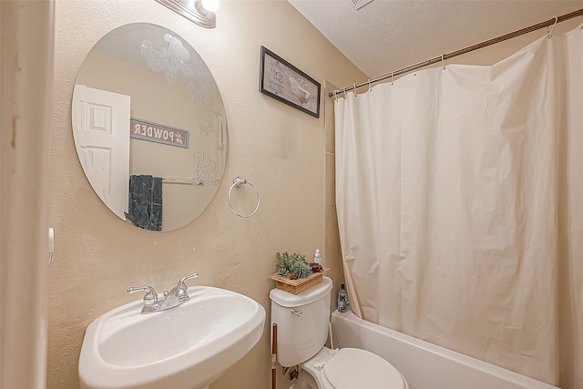 full bathroom featuring a textured ceiling, shower / bath combination with curtain, toilet, and sink