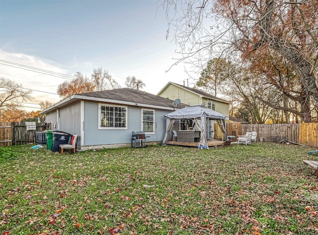 rear view of property with a gazebo, a wooden deck, and a lawn