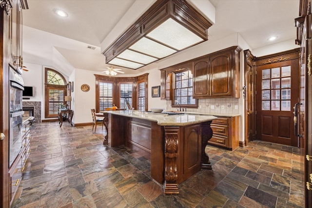 kitchen featuring ceiling fan, sink, tasteful backsplash, oven, and a kitchen island