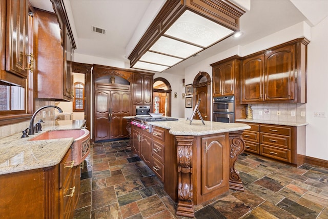 kitchen with light stone countertops, appliances with stainless steel finishes, backsplash, and a kitchen island