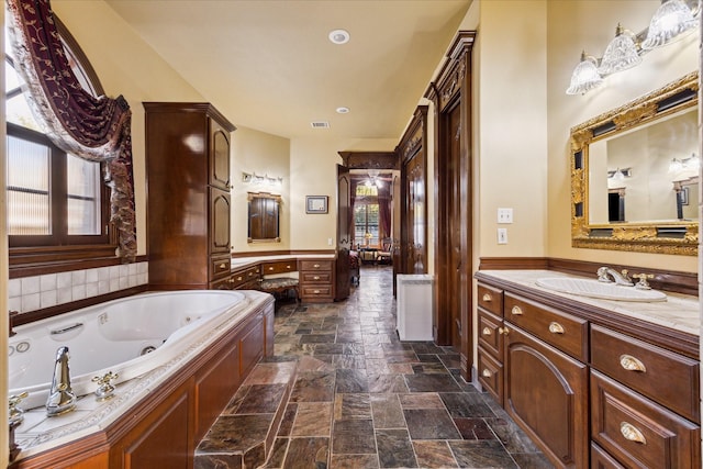 bathroom featuring a bathing tub, vanity, and a wealth of natural light