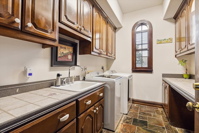 laundry area with washing machine and clothes dryer, sink, and cabinets