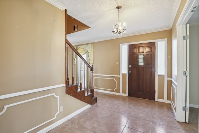 tiled entryway featuring ornamental molding, a chandelier, and a textured ceiling