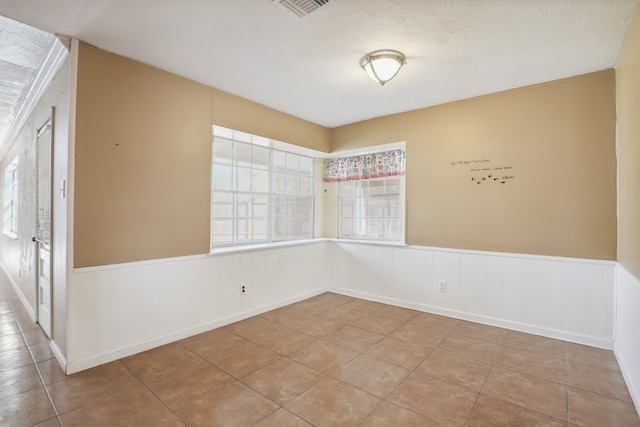 spare room with a textured ceiling and light tile patterned floors