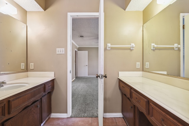 bathroom featuring tile patterned flooring, vanity, ornamental molding, and a textured ceiling