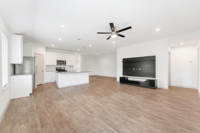 kitchen featuring a kitchen island with sink, white cabinetry, light wood-type flooring, and appliances with stainless steel finishes