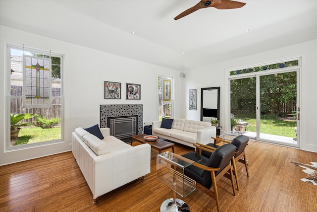 living room with ceiling fan, light hardwood / wood-style floors, and a tile fireplace