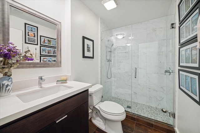 bathroom featuring toilet, vanity, tile patterned floors, and a shower with door