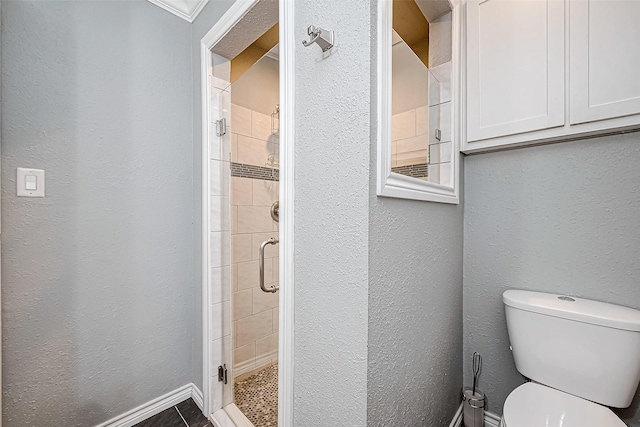 bathroom with ornamental molding, an enclosed shower, and toilet