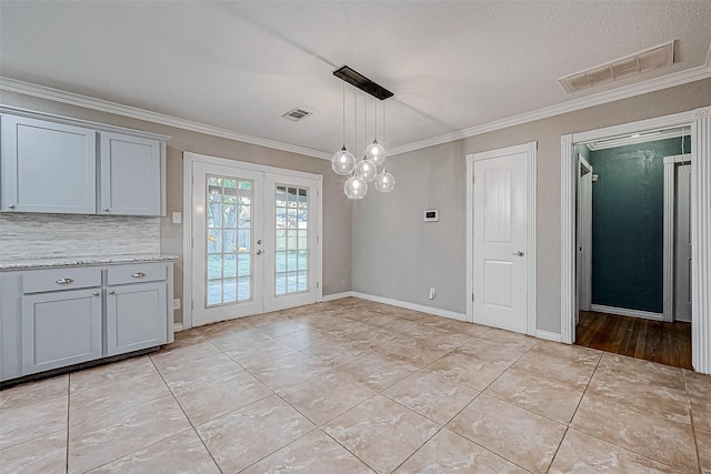 unfurnished dining area with a textured ceiling, light tile patterned floors, crown molding, and french doors