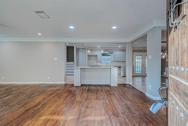 kitchen with sink, crown molding, dark hardwood / wood-style floors, decorative backsplash, and light stone countertops