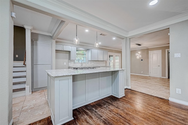 kitchen featuring light stone countertops, light hardwood / wood-style flooring, a kitchen island, and hanging light fixtures