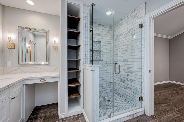 bathroom with hardwood / wood-style floors, vanity, a shower with door, and ornamental molding