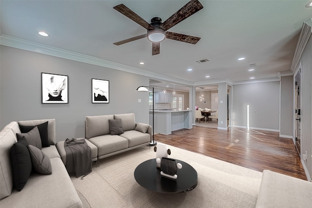 living room featuring ceiling fan, ornamental molding, and light hardwood / wood-style flooring