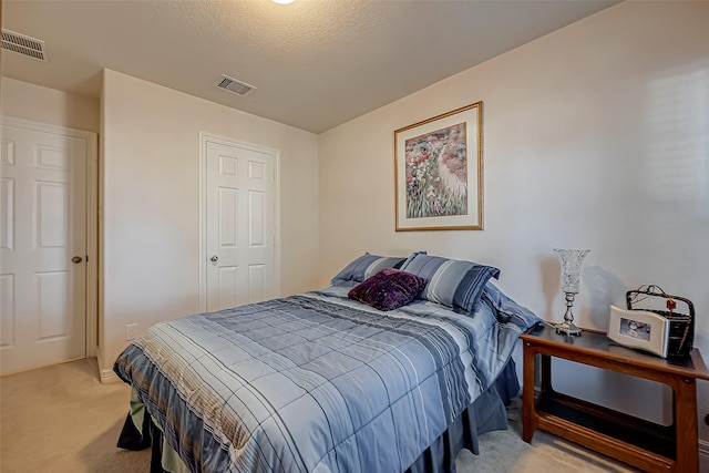 bedroom with light carpet, visible vents, and a textured ceiling