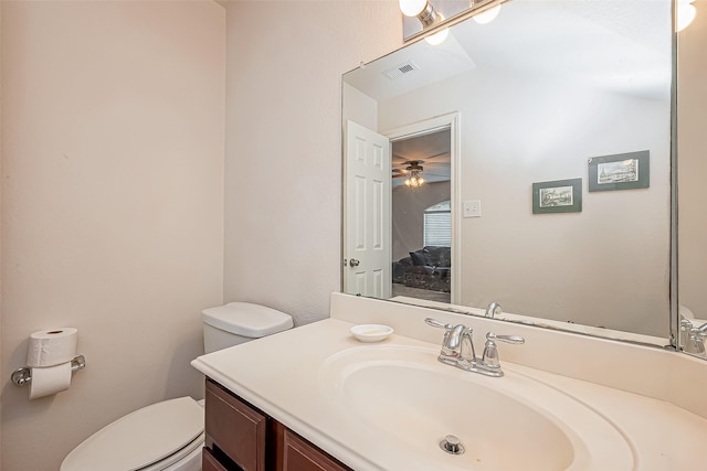 half bath featuring visible vents, toilet, vanity, and ceiling fan