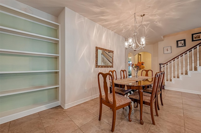 dining space with built in features, stairway, arched walkways, an inviting chandelier, and light tile patterned floors