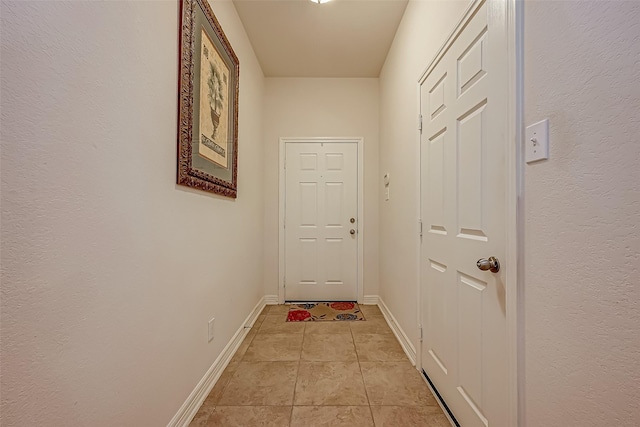 hallway with light tile patterned floors and baseboards