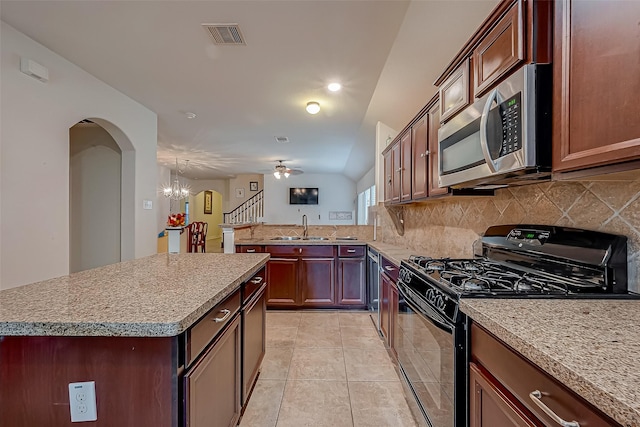 kitchen with decorative backsplash, stainless steel microwave, arched walkways, and black range with gas stovetop