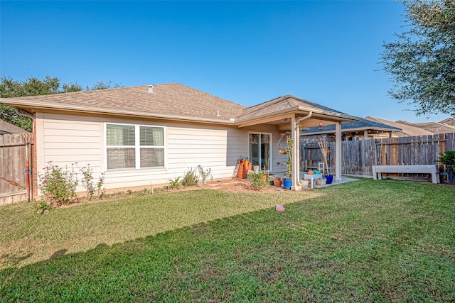 back of property featuring roof with shingles, a yard, and fence