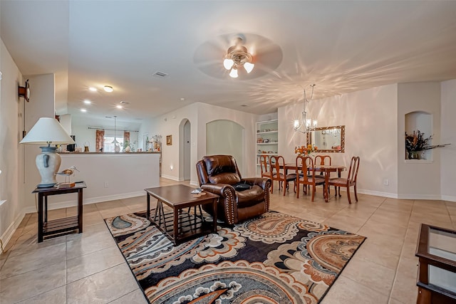 living room featuring visible vents, built in shelves, light tile patterned floors, ceiling fan with notable chandelier, and arched walkways