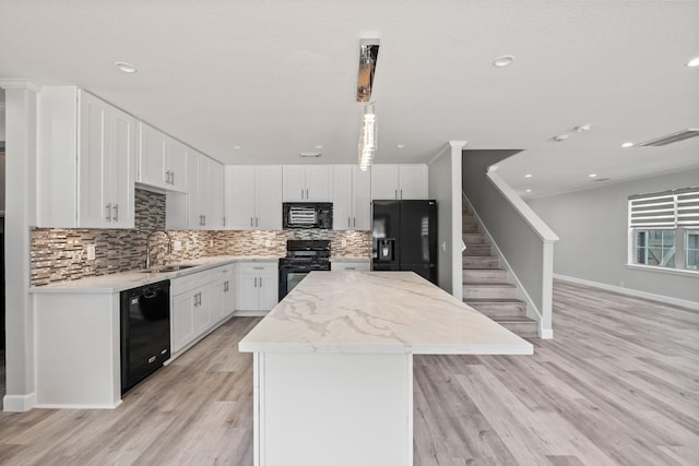 kitchen featuring white cabinetry, sink, a center island, black appliances, and light wood-type flooring