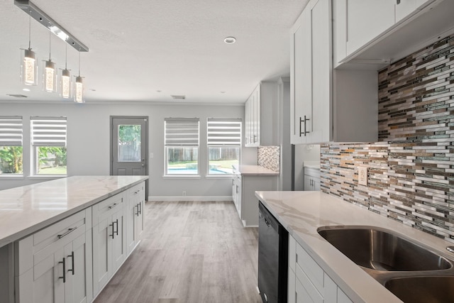 kitchen featuring dishwasher, light stone counters, backsplash, light hardwood / wood-style floors, and white cabinets