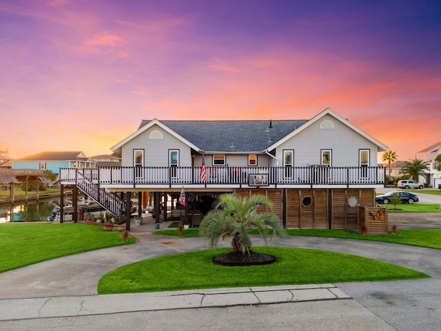 view of front of property featuring a carport, a deck with water view, and a lawn