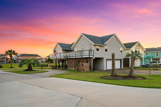 view of front facade with a garage, a deck, and a lawn