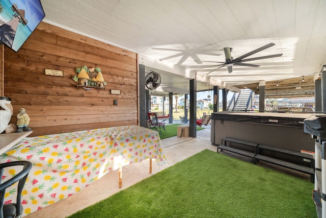 carpeted bedroom with ceiling fan and wood walls