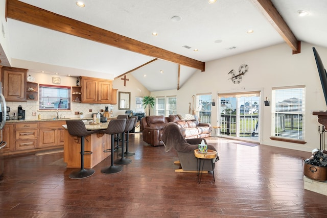 living room featuring beamed ceiling, plenty of natural light, sink, and dark wood-type flooring