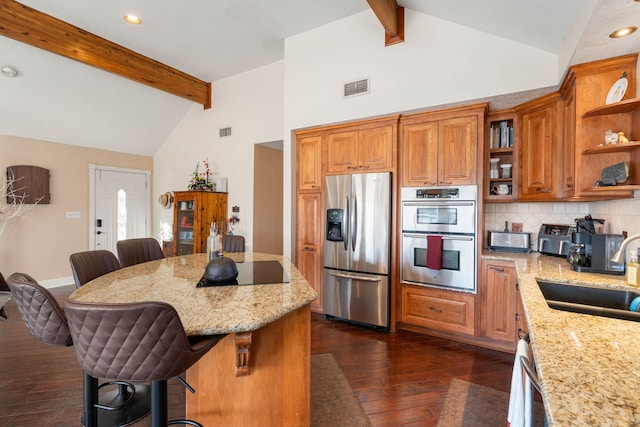 kitchen with a breakfast bar, dark wood-type flooring, sink, appliances with stainless steel finishes, and beamed ceiling