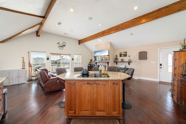 kitchen featuring dark hardwood / wood-style flooring, lofted ceiling with beams, a textured ceiling, a kitchen bar, and a kitchen island