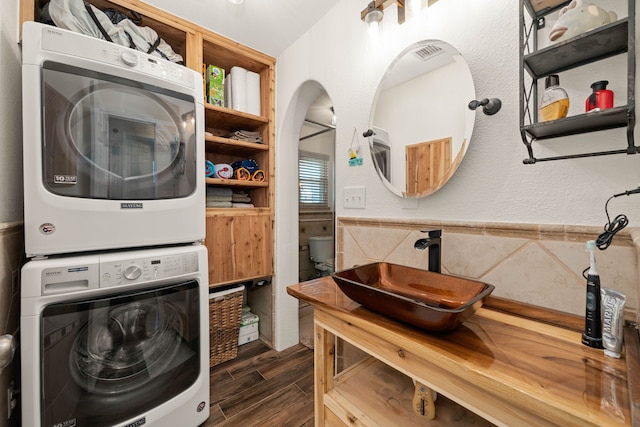 laundry room with sink, dark hardwood / wood-style floors, and stacked washer and clothes dryer